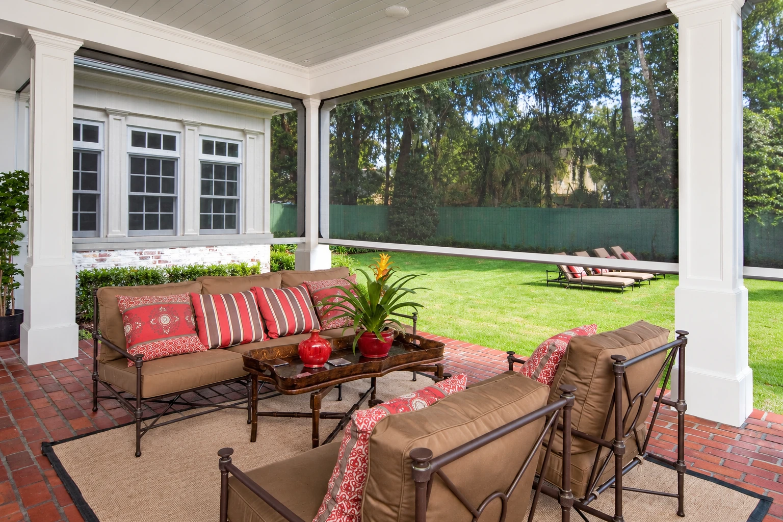 Covered patio with white columns, screened sides, and brown seating on a brick floor.