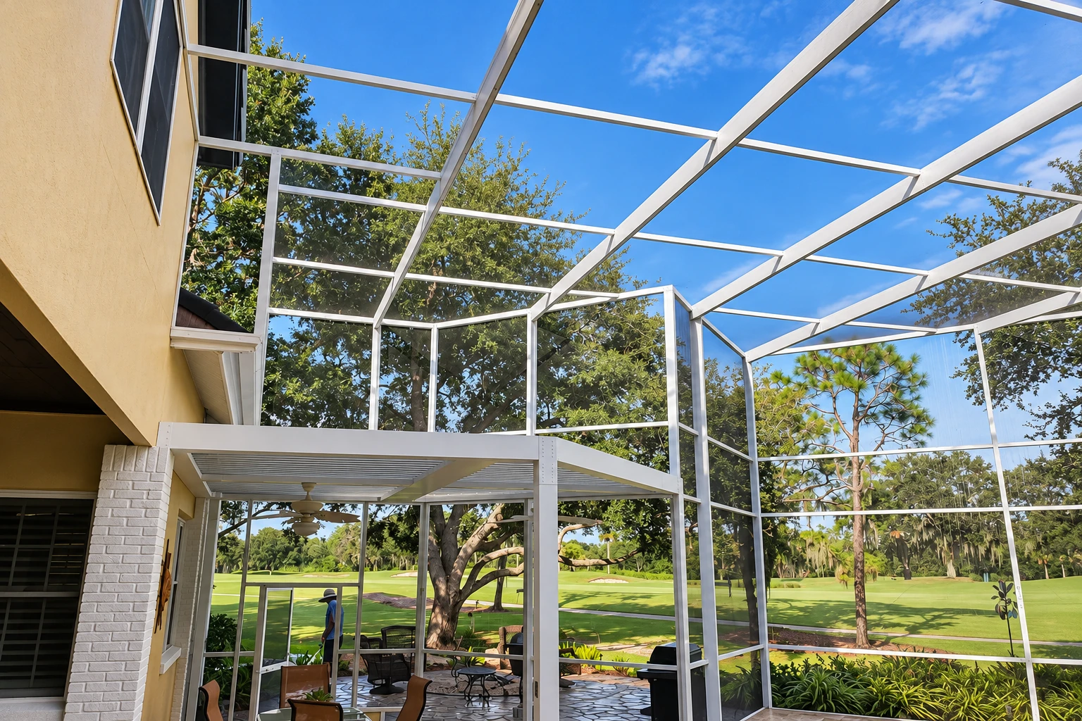 White-framed screened patio cover attached to a house, with open views of trees and a green lawn.