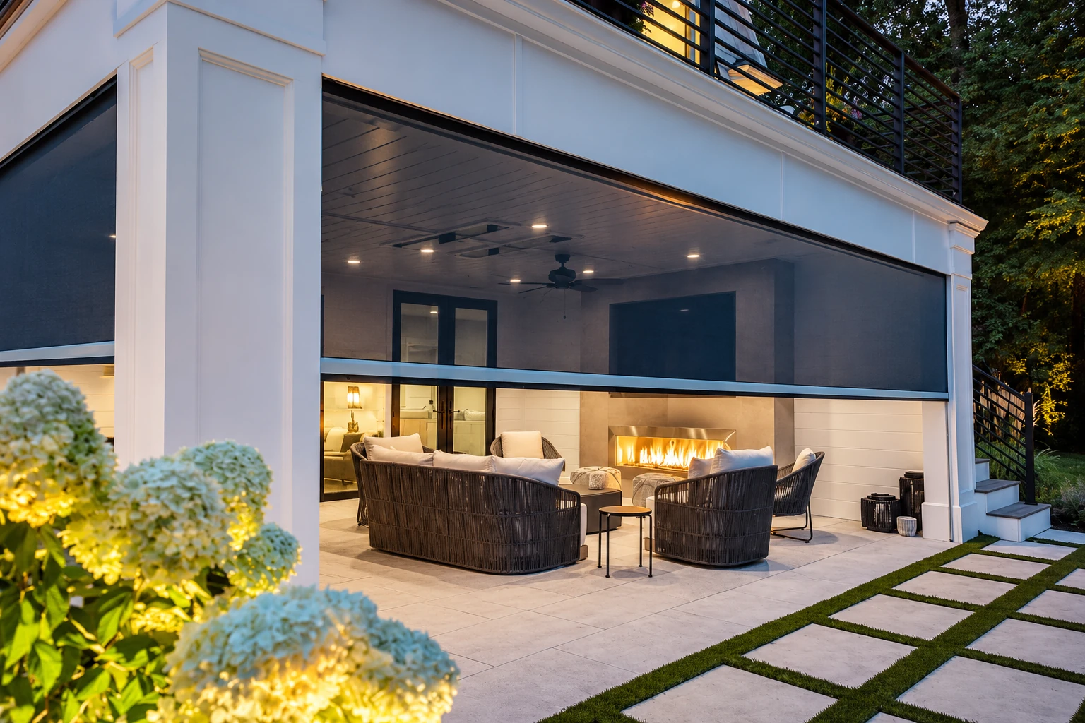 Screened patio with black mesh panels, wicker seating, and a lit fireplace beneath a covered ceiling.